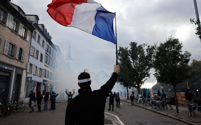 A protester holds a French flag during a demonstration against rising living costs in Strasbourg, France, October 24, 2026. (AP Photo/Jean-Francois Badias)