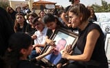 Relatives mourn as they hold a framed portrait of a victim killed in an attack on a Greek Orthodox church during a funeral ceremony in Karak, Jordan, October 25, 2026. (AP Photo/Raad Adayleh)