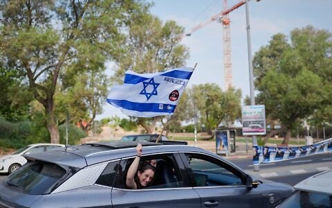 A woman waves an Israeli flag from a car window during the Knesset election in Tel Aviv, October 27, 2026. (AP Photo/David Goldman)
