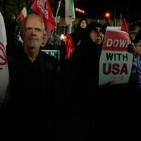 A demonstrator holds an anti-US placard as another holds an Iranian flag during a pro-government gathering in Tehran, Iran, October 27, 2026. (AP Photo/Vahid Salemi)