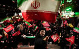 A cleric waves an Iranian flag while leading demonstrators during a pro-government gathering in Tehran, Iran, October 27, 2026. (AP/Vahid Salemi)