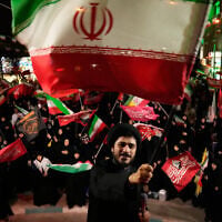 A cleric waves an Iranian flag while leading demonstrators during a pro-government gathering in Tehran, Iran, October 27, 2026. (AP/Vahid Salemi)