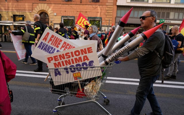 A demonstrator pushes a shopping cart carrying mock missiles and placards calling for a minimum pension of 1,000 euros during a nationwide general strike called by grassroots unions to protest rising living costs, low wages and military spending in Rome, Italy, October 30, 2026. (AP Photo/Gregorio Borgia) A demonstrator pushes a shopping cart carrying mock missiles and placards calling for a minimum pension of 1,000 euros during a nationwide general strike called by grassroots unions to protest rising living costs, low wages and military spending in Rome, Italy, October 30, 2026. (AP Photo/Gregorio Borgia)