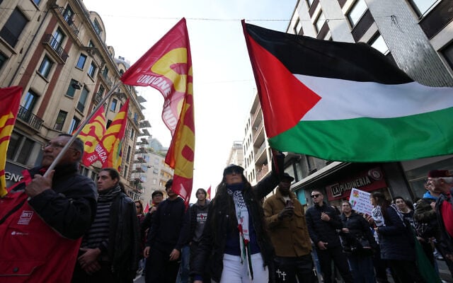 Workers, students and activists with a Palestinian flag demonstrate during a nationwide general strike called by grassroots unions to protest rising living costs, low wages and military spending, October 30, 2026, in Milan. (AP Photo/Antonio Calanni)