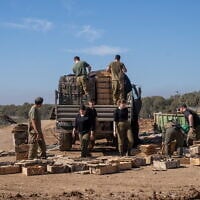 Combat support soldiers are seen loading explosives onto an army vehicle outside the Paga military post on the border with the Gaza Strip, December 15, 2023. (Emanuel Fabian/Times of Israel)
