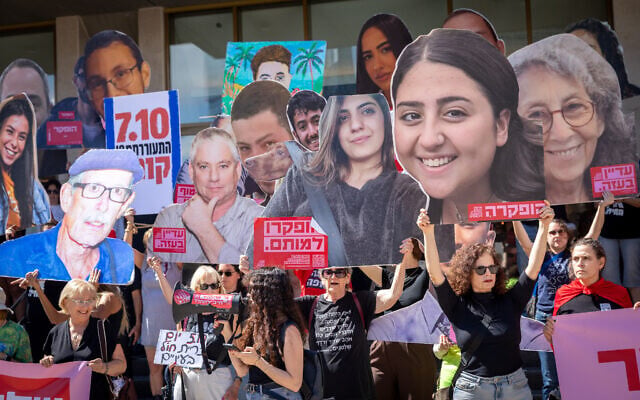 People hold images of Israelis killed by terrorists during and after the October 7 massacre, at Hostages Square in Tel Aviv. October 7, 2026. (Miriam Alster/FLASH90)