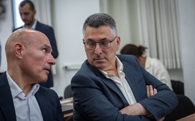 Foreign Minister Gideon Sa’ar (R) speaks with Efi Nave at the Jerusalem District Court at a hearing for the corruption trial of Prime Minister Benjamin Netanyahu, October 11, 2026. (Chaim Goldberg/Flash90)