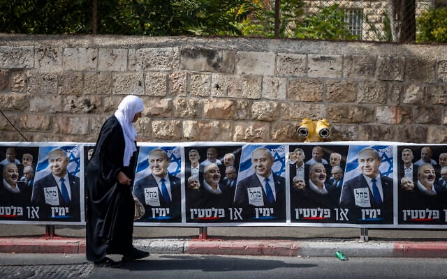 A Muslim woman walks past a Likud party election campaign billboard featuring Prime Minister Benjamin Netanyahu alongside opposition leaders and the slogan 'Right or Palestine,' in East Jerusalem, October 12, 2026. (Yonatan Sindel/Flash90)
