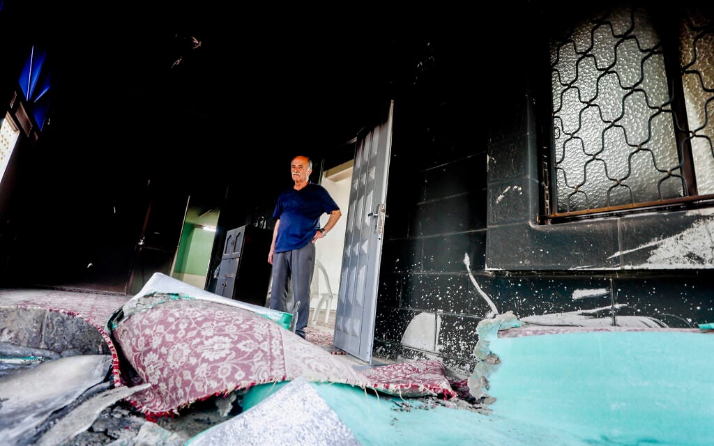 A Palestinian man inspects a damaged mosque following an alleged attack by settlers in the village of Mukhmas, northeast of Jerusalem, October 14, 2026. (Jamal Awad/Flash90)