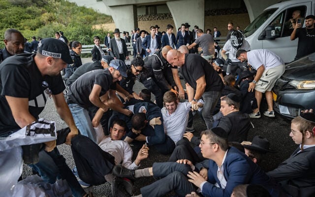 Ultra-Orthodox Jewish men clash with police officers and civilians as they block a road during a protest against the jailing of yeshiva students who failed to comply with an army recruitment order, at the Yavne Interchange on Route 4, October 18, 2026. (Chaim Goldberg/Flash90)