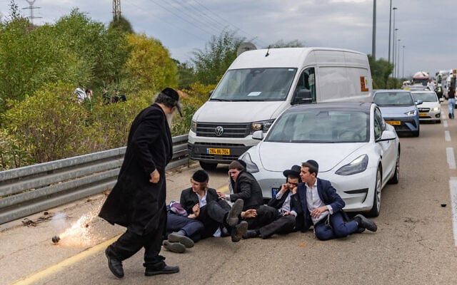 Ultra-Orthodox Jewish men clash with police officers and civilians as they block a road during a protest against the jailing of yeshiva students who failed to comply with an army recruitment order, at the Yavne Interchange on Route 4, October 18, 2026. (Chaim Goldberg/Flash90)