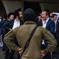 Ultra-Orthodox Jewish men clash with police officers and soldiers as they block a road during a protest against the jailing of yeshiva students who failed to comply with an army recruitment order, at the Yavne Interchange on Route 4, October 18, 2026. (Chaim Goldberg/Flash90)
