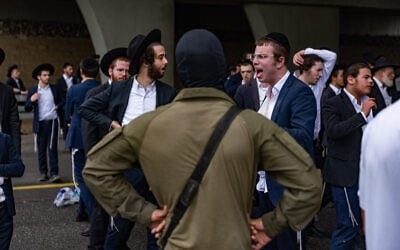 Ultra-Orthodox Jewish men clash with police officers and soldiers as they block a road during a protest against the jailing of yeshiva students who failed to comply with an army recruitment order, at the Yavne Interchange on Route 4, October 18, 2026. (Chaim Goldberg/Flash90)