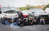 A stun grenade appears to explode next to ultra-Orthodox demonstrators during clashes with police officers and civilians as they blocked Route 4 during a protest against the jailing of yeshiva students who failed to comply with an army recruitment order, at the Yavne Interchange, October 18, 2026. (Chaim Goldberg/Flash90)