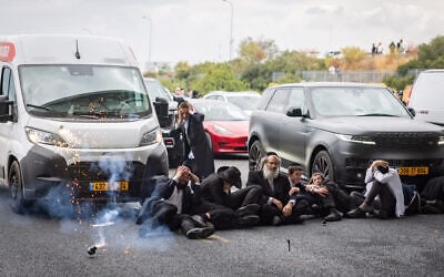 A stun grenade appears to explode next to ultra-Orthodox demonstrators during clashes with police officers and civilians as they blocked Route 4 during a protest against the jailing of yeshiva students who failed to comply with an army recruitment order, at the Yavne Interchange, October 18, 2026. (Chaim Goldberg/Flash90)