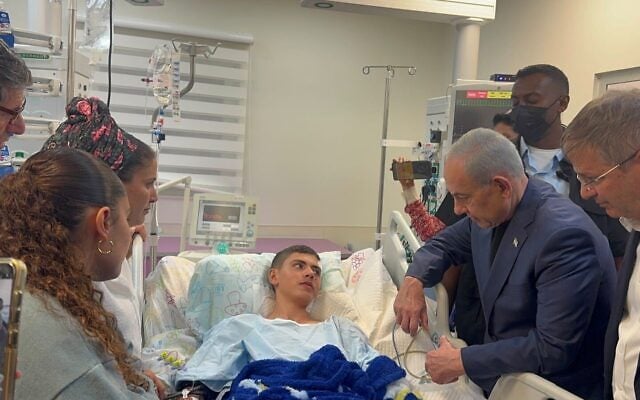 Prime Minister Benjamin Netanyahu (second from right) and Education Minister Yoav Kisch (right) visit the hospital bed of a teenager injured in an explosion caused by an unexploded Hezbollah ordnance during a school hike in the north, October 12, 2026. (Prime Minister's Office) Prime Minister Benjamin Netanyahu (second from right) and Education Minister Yoav Kisch (right) visit the hospital bed of a teenager injured in an explosion caused by an unexploded Hezbollah ordnance during a school hike in the north, October 12, 2026. (Prime Minister's Office)
