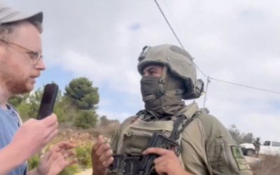 A masked soldier confronts an activist with Rabbis for Human Rights during the olive harvest season near Birzeit, close to Ramallah in the central West Bank, on October 9, 2026. (Screen capture: X/Rabbis for Human Rights)