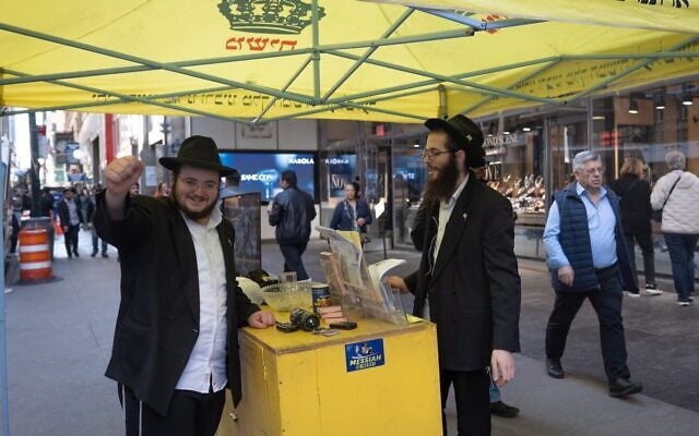 Shmuel Cohen (left) takes a break from wrapping tefillin with passersby in New York City's Diamond District on October 23, 2026. (Joseph Strauss/JTA)