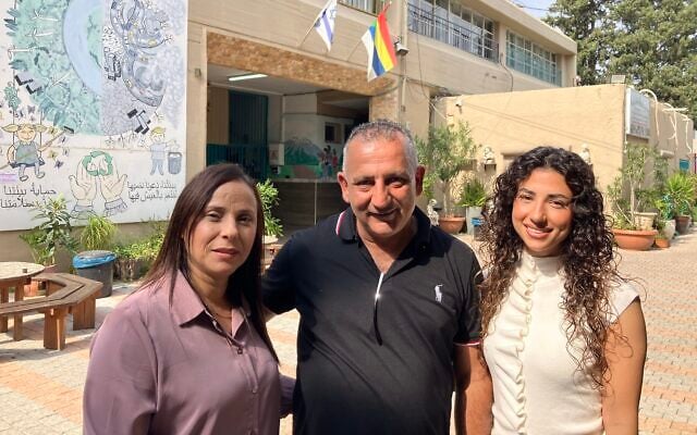 Najla Mula, left, stands outside the polling station in Yarka with her husband, Wassim Mula, and their daughter, Merna, with a Druze flag and an Israeli flag behind them on October 27, 2026. (Diana Bletter/Times of Israel) Najla Mula, left, stands outside the polling station in Yarka with her husband, Wassim Mula, and their daughter, Merna, with a Druze flag and an Israeli flag behind them on October 27, 2026. (Diana Bletter/Times of Israel)