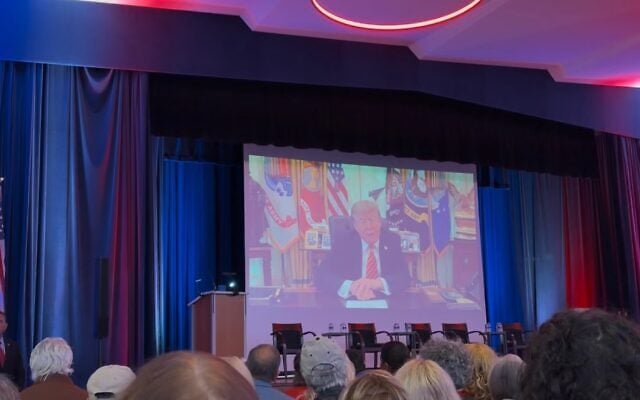US President Donald Trump addresses Congregation Shaarey Zedek by video as part of an event to address antisemitism in Southfield, Michigan, October 14, 2026. (Andrew Lapin/JTA)